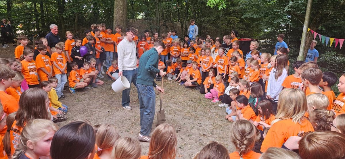 Viele Kinder schauen Betreuer beim Spatenstich zu
